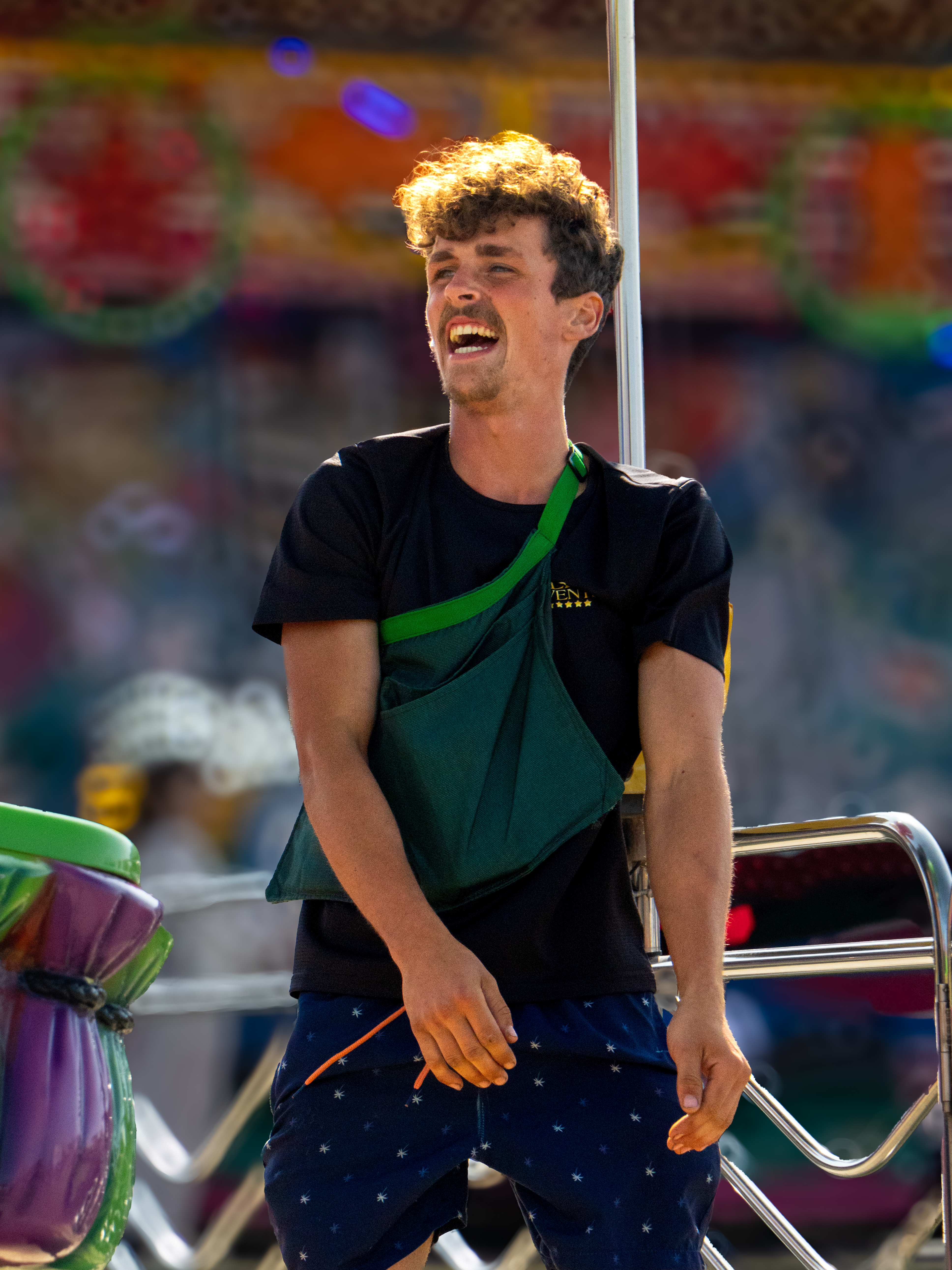 Young man laughing at fairground during golden hour